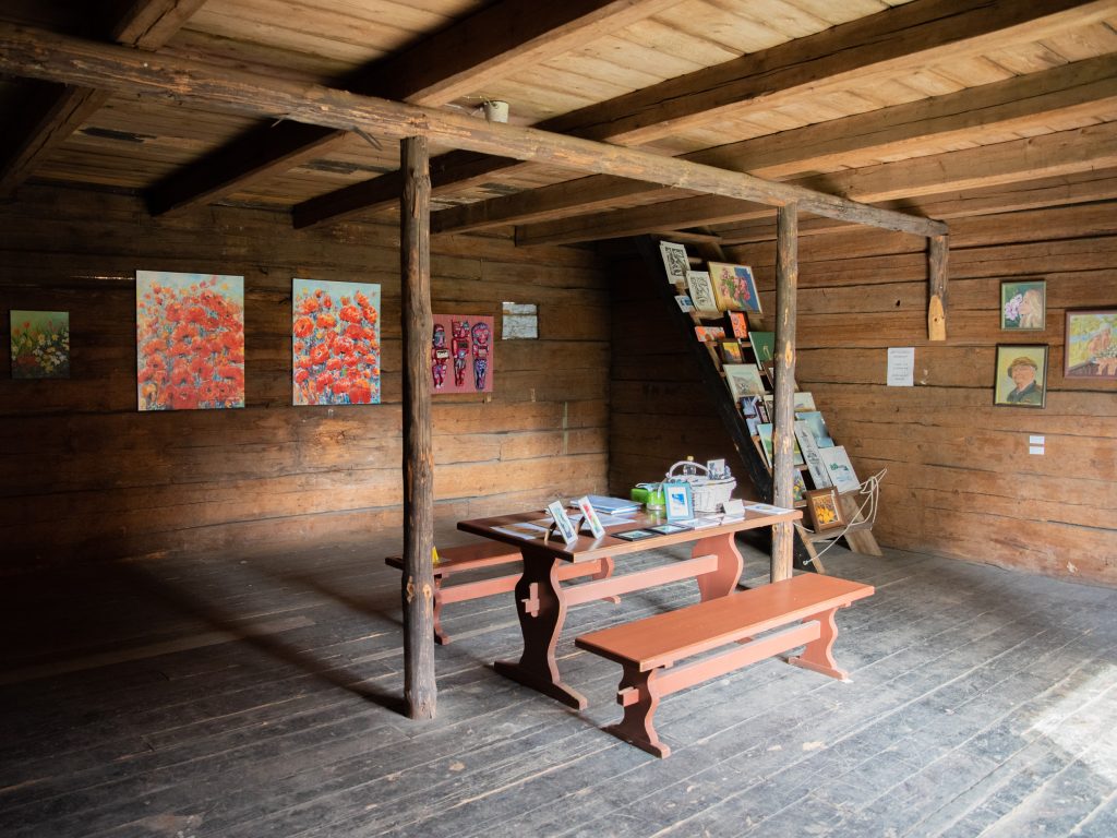 Hirsisen aittarakennuksen sisätilat. Keskellä huonetta pirtin pöytä ja penkit. 